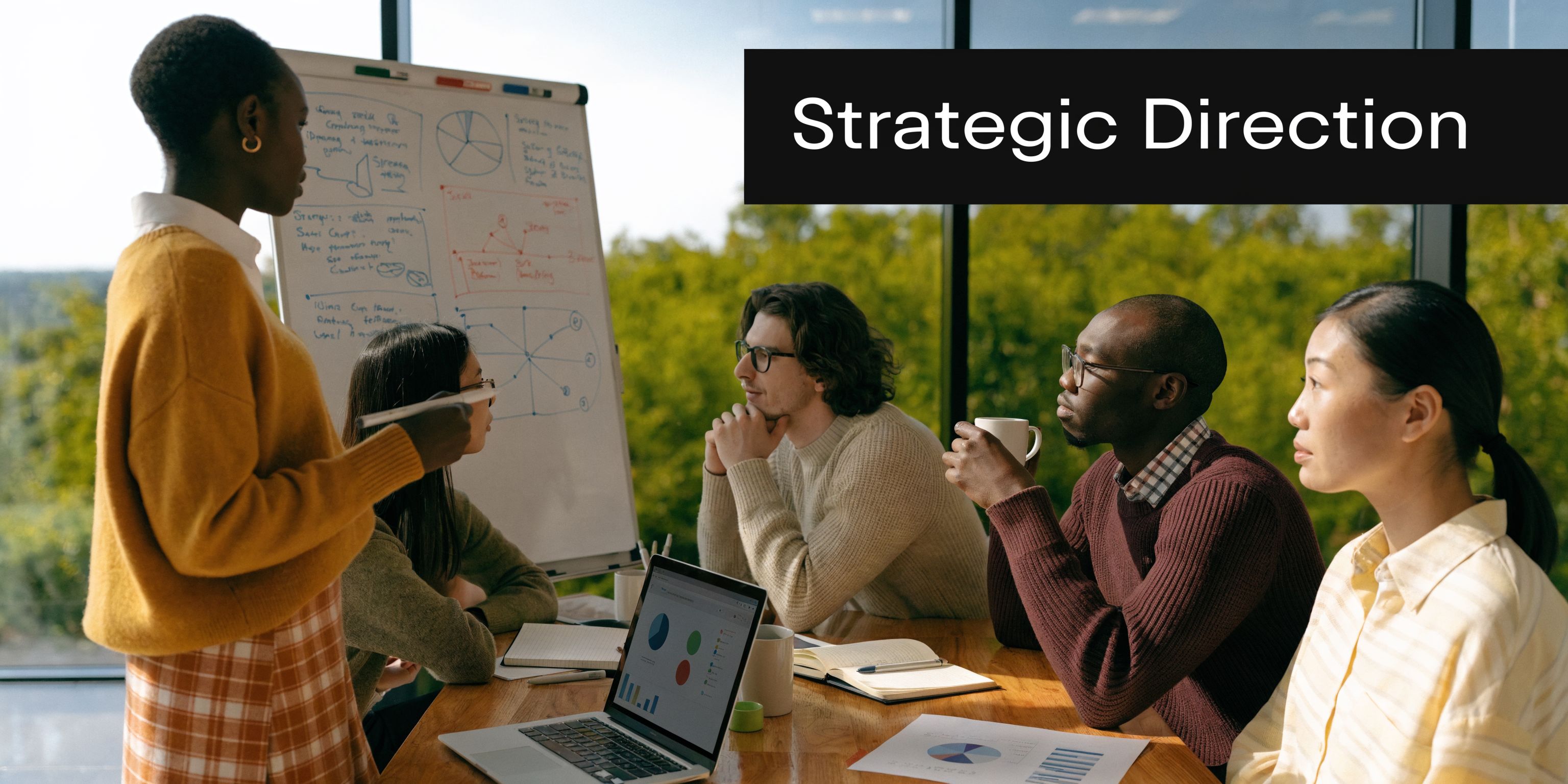 A group of diverse professionals having a collaborative business meeting with a whiteboard and laptop in an office.