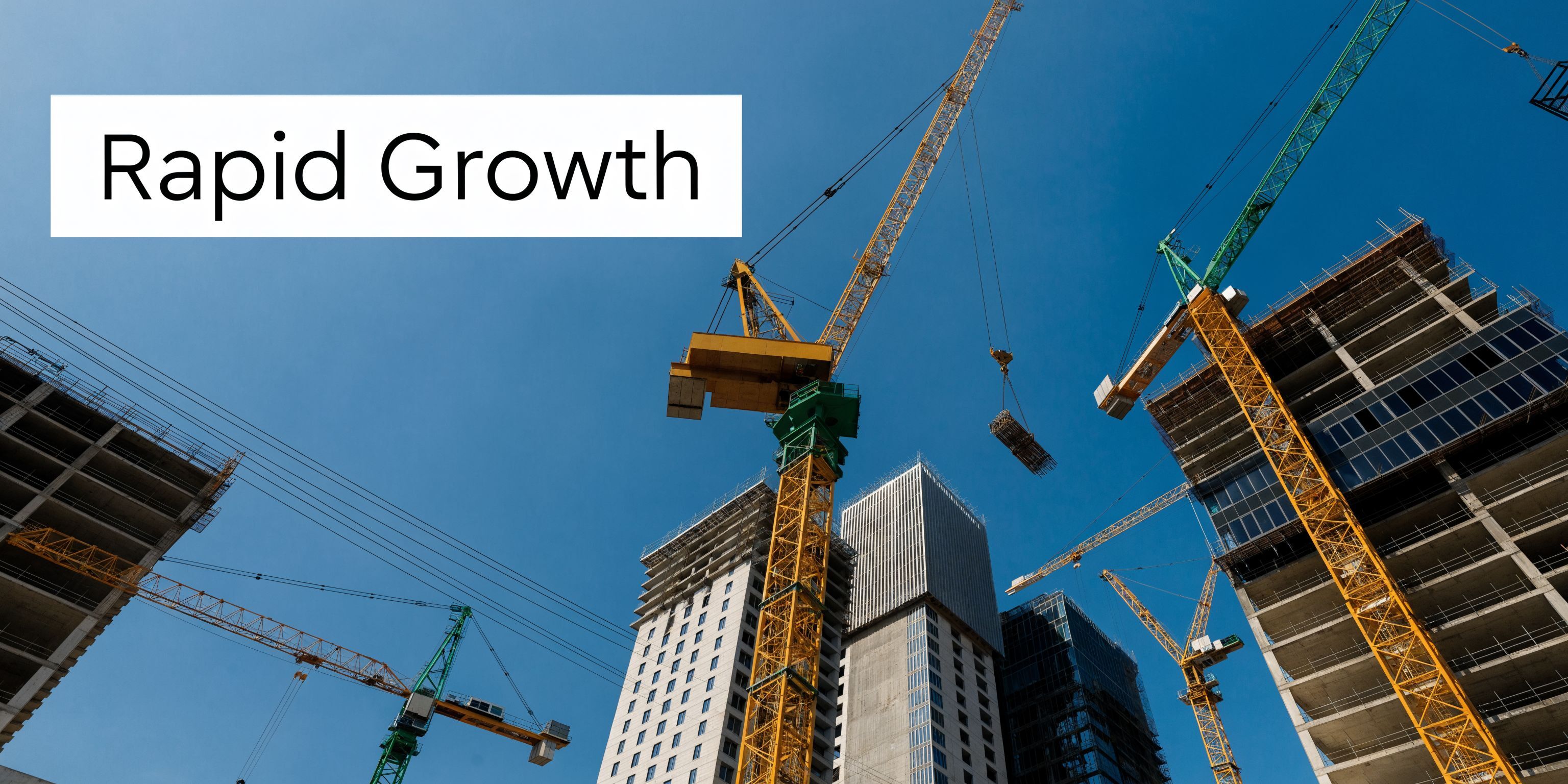 Low angle view of several tall construction cranes operating at a large city building project site.