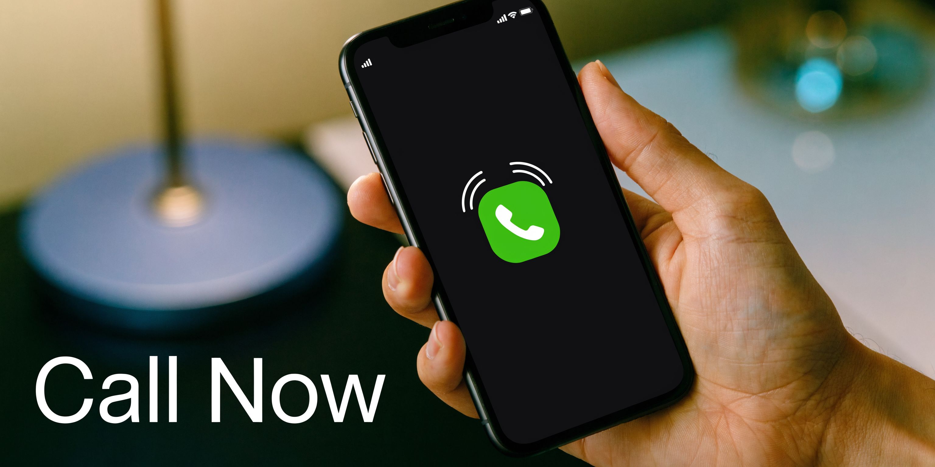 A close-up of a person's hand holding a smartphone displaying a green incoming call icon.